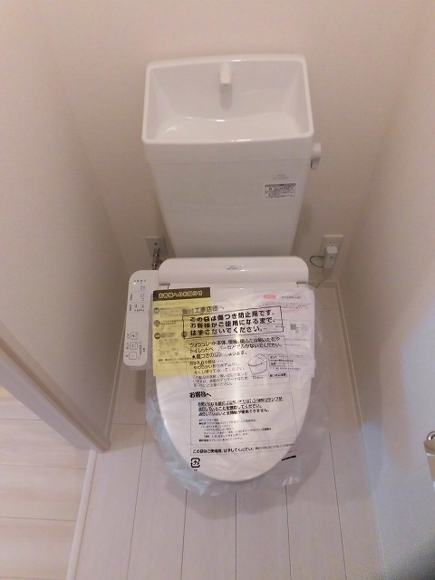 温水洗浄便座機能付きトイレ。上部に収納棚があります。 温水洗浄便座機能付きトイレ。上部に収納棚があります。